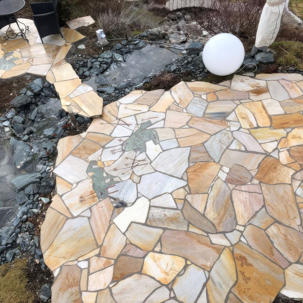 Individuell gestaltete Natursteinterrasse mit Teich und Mosaikelementen